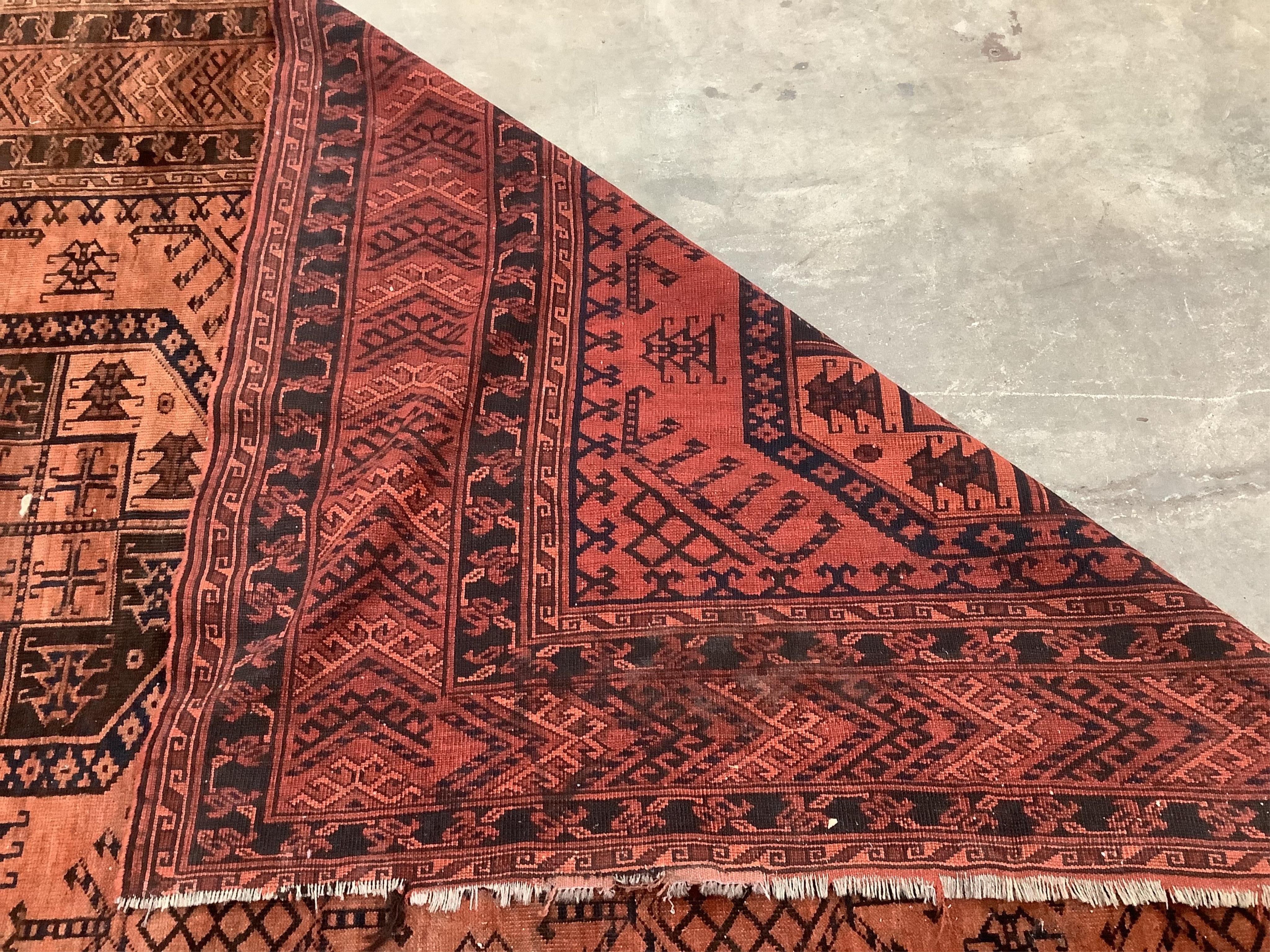 An Afghan rust ground carpet, 400 x 260cm. Condition - poor, damage to border